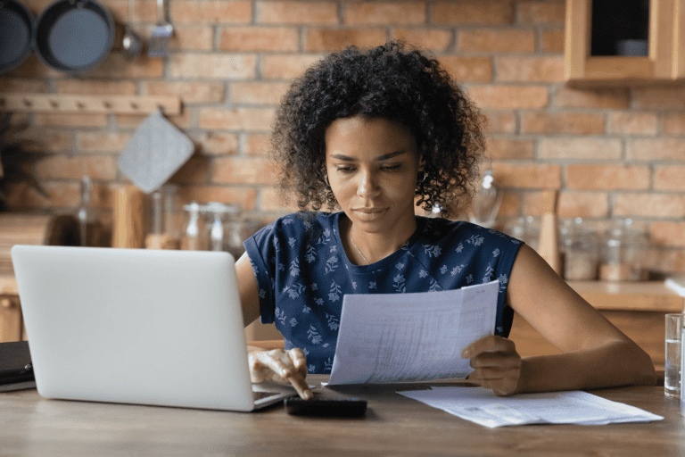 A lady calculating her bills with laptop and calculator