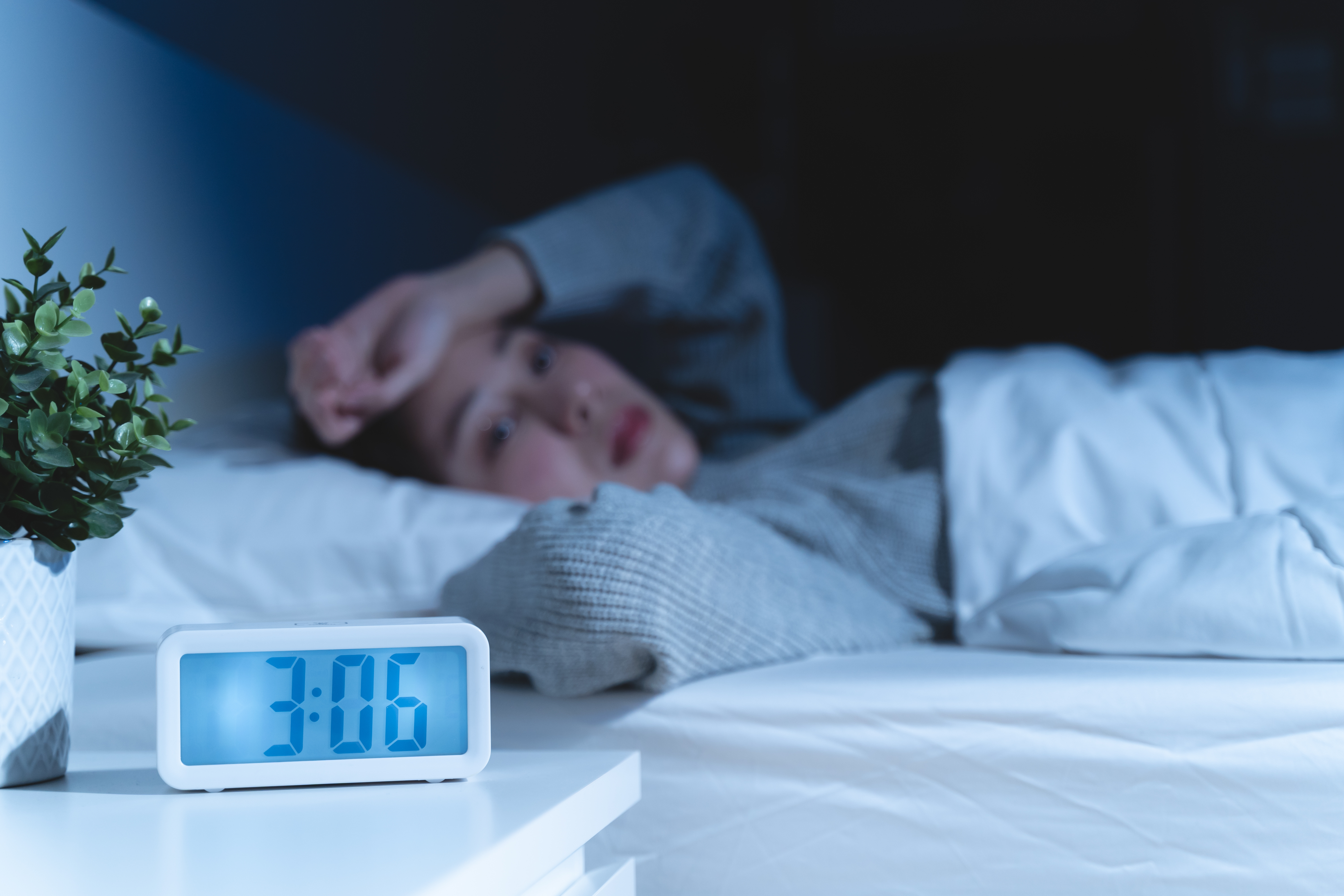 Woman can't sleep because of the Menopause and hot flushes. Alarm clock says time is 3:06am 