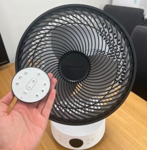 A person holds a circular remote control in front of a Meaco fan