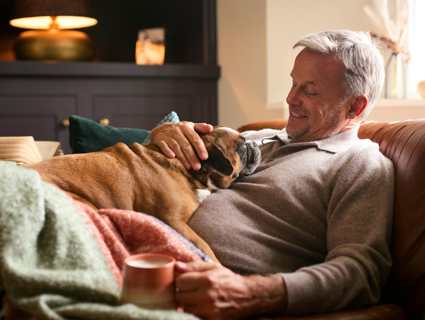 Autumn Heating bills - man and his dog cosy on the sofa