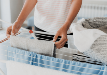 Woman hanging laundry on a clothes airer indoors