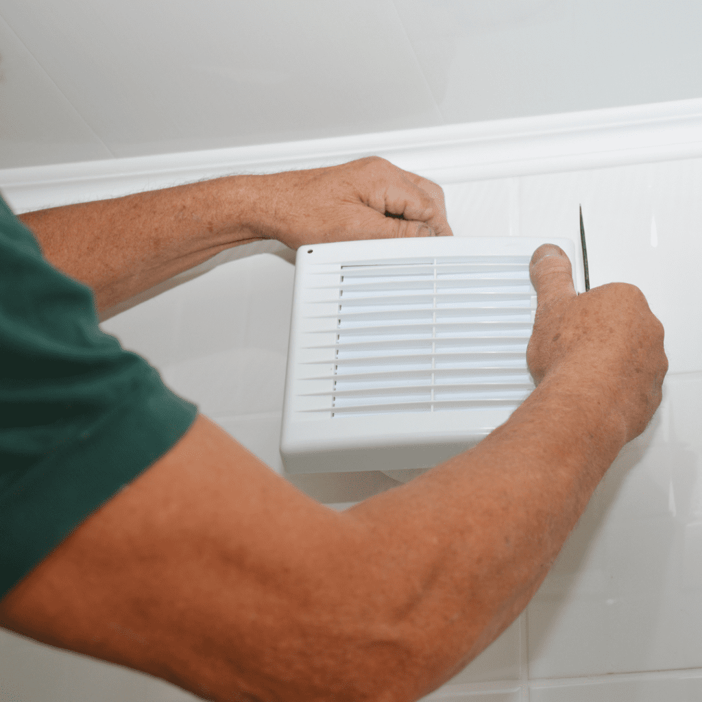 Handyman installing extraction fan in bathroom humidity management dehumidification