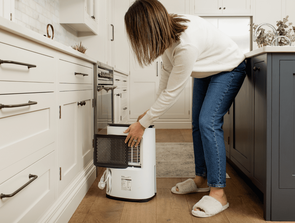 Arete Two Dehumidifier and Air Purifier woman taking out the filter (landscape)