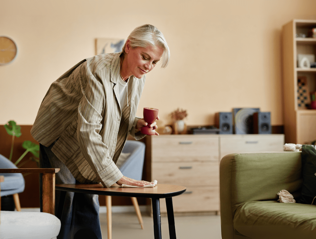 Elegant lady cleaning up dust from the living room coffee table