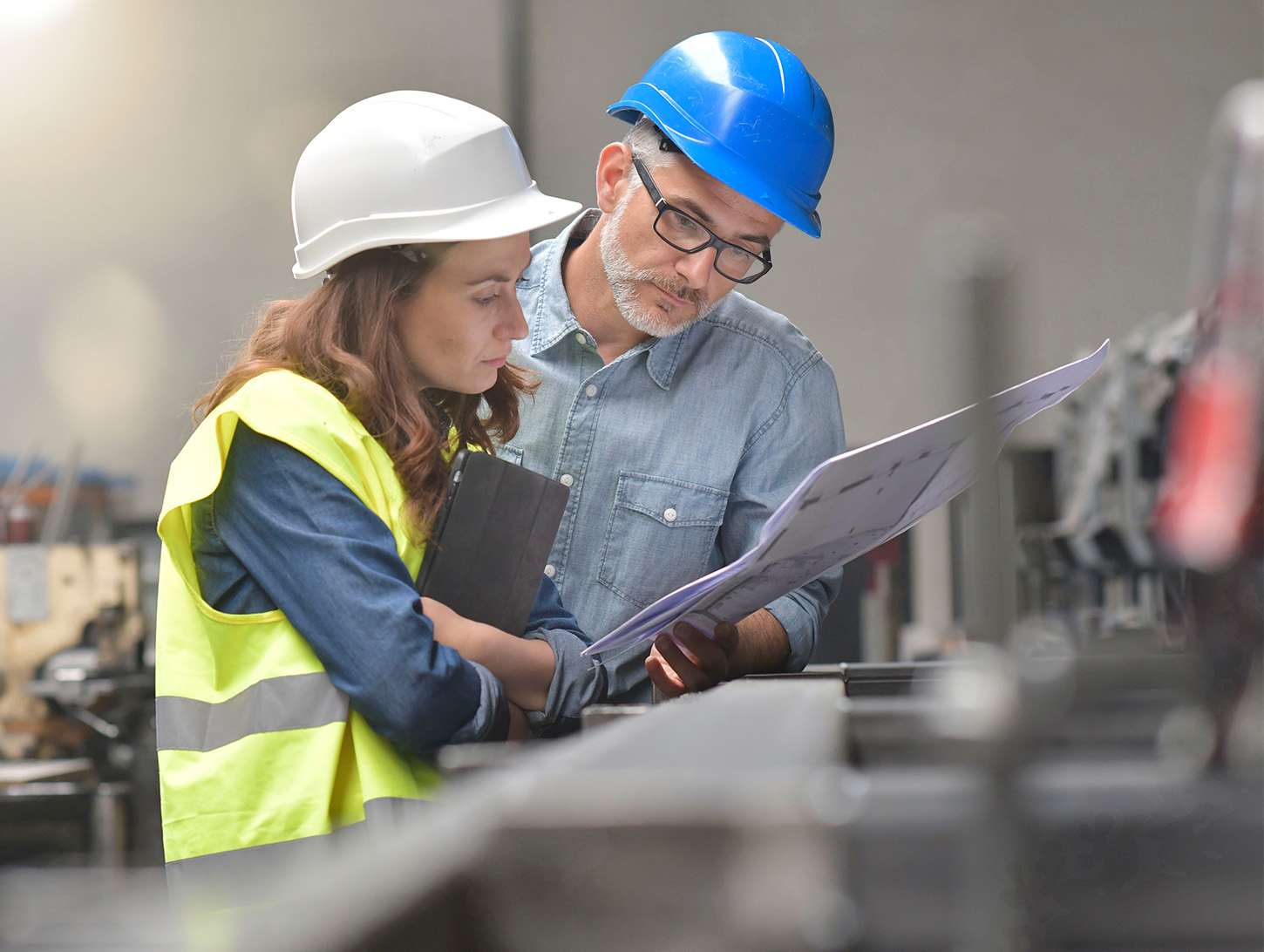 Male and female engineers reviewing a report with high vis and helmets