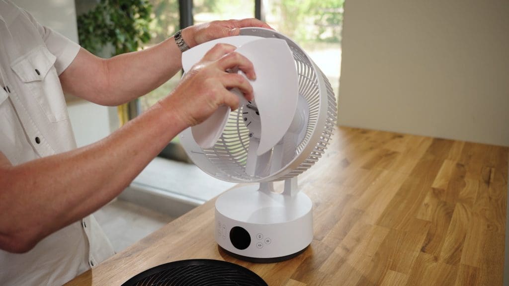 Hands removing the fan blade from the fan